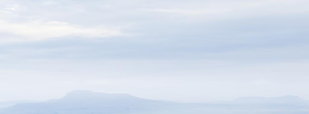 The distinctive shapes of Ingleborough and Pen-y-Ghent—two of the Yorkshire Three Peaks—in the morning haze