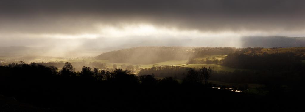 The Winster Valley illuminated by crepuscular rays through dark clouds